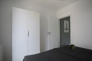 a bedroom with white walls and a black bed at AL-DOM apartamenty Kniewskiego 11 Kolobrzeg in Kołobrzeg