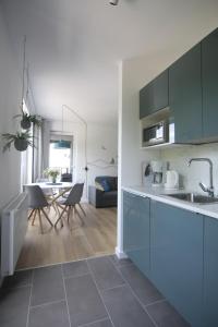 une cuisine avec des armoires bleues et une salle à manger dans l'établissement AL-DOM apartamenty Kniewskiego 11 Kolobrzeg, à Kołobrzeg