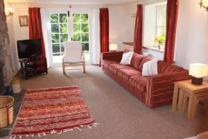 a living room with a red couch and a television at Church Hill Farm in Monmouth