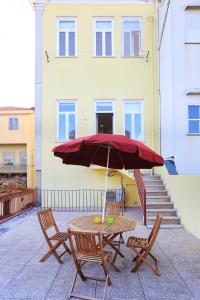 einen Tisch und Stühle mit einem Regenschirm vor einem Gebäude in der Unterkunft Bright Sao Domingos Apartments in Viana do Castelo