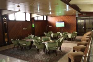 una sala de espera con mesas, sillas y una pantalla en Hotel Imperial, en Aveiro