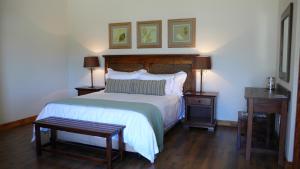 1 dormitorio con 1 cama, 2 mesas y 2 cuadros en la pared en Honeylocust Guesthouse, en Colesberg