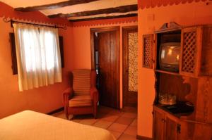 a bedroom with a bed and a tv and a chair at Hotel la Casa del Abuelo in Albarracín