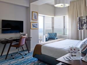 a hotel room with a bed and a desk and a television at Shelborne South Beach in Miami Beach