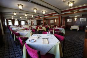 a dining room with white tables and pink chairs at Hotel Imperial in Aveiro