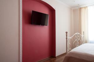 リヴィウにあるApartment Roksolana 2の赤い壁のベッドルーム(テレビ付)