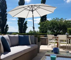 a white couch and an umbrella on a patio at Le Manoir de Herouville in Litteau