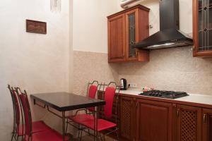 cocina con fogones y mesa con sillas rojas en Apartment Roksolana, en Leópolis