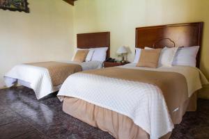 ein Hotelzimmer mit 2 Betten mit weißer und brauner Bettwäsche in der Unterkunft El Cano in Guaillabamba