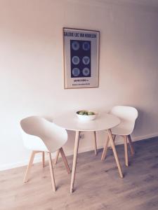 
a white table topped with white chairs next to a wall at Studio Ostend Living in Ostend
