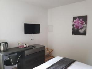 a bedroom with a bed and a desk and a tv at Hotel Restaurant Pavillon Bleu in Olivet