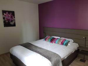 ein Schlafzimmer mit einem Bett mit einer lila Wand in der Unterkunft Hotel Restaurant Pavillon Bleu in Olivet