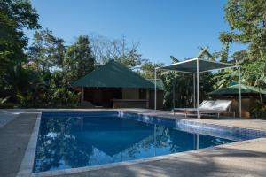 a swimming pool with a gazebo and a house at Rancho Capulin B&B in Tárcoles