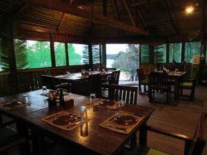 a dining room with tables and chairs and windows at Dolphin Lodge in Careiro