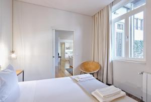a white bedroom with a bed and a window at Casas do Rivoli in Porto