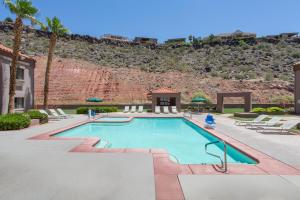 a swimming pool in a resort with a hill in the background at Ramada by Wyndham St George in St. George