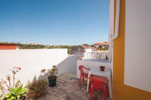 a small balcony with red chairs and a table at Rivers Nation Surf Camp in Atouguia da Baleia