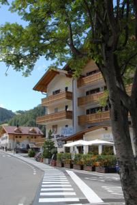 a building on the side of a street with a tree at Hotel Italia in Corvara in Badia