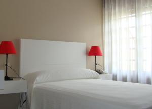 a bedroom with a white bed with two red lamps at Hotel Chancelas in Chancelas