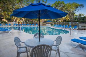 einen Tisch mit einem blauen Regenschirm neben einem Pool in der Unterkunft Carolina Club by Spinnaker Resorts in Hilton Head Island