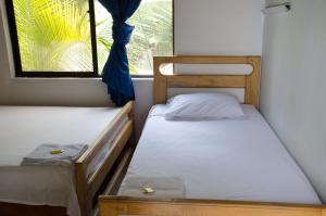 2 camas en una habitación pequeña con ventana en Hospedaje la Glorieta, en Santa Fe de Antioquia