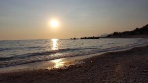 a beach with the sun setting over the water at Triantis Apartments in Ligia