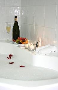 a bath tub with a bottle of wine and a glass at The Wellington Apartment Hotel in Brisbane