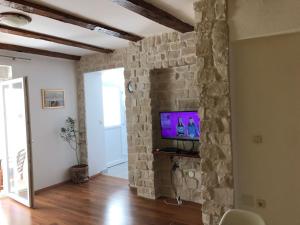 a living room with a stone wall and a television at Apartment Bruno in Šibenik