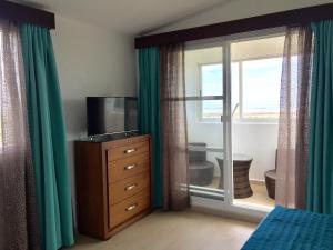 1 dormitorio con TV, vestidor y ventana en Ananta Hotel, en Casitas