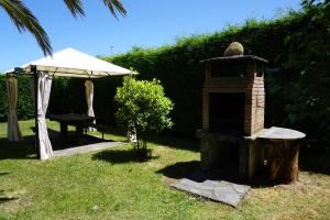 un horno de ladrillo en la hierba con una mesa y una sombrilla en Casa Gayol en El Franco
