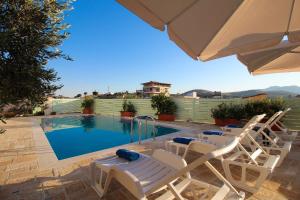 a group of chairs and an umbrella next to a swimming pool at Villa Aleandro in Ksamil