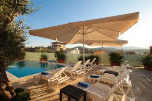 a group of chairs and an umbrella next to a pool at Villa Aleandro in Ksamil