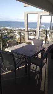una mesa y sillas en un balcón con vistas al océano en Maroochy Sands Holiday Apartments, en Maroochydore