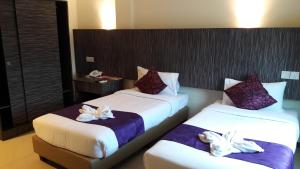two beds in a hotel room with flowers on them at Salsa Resort Langkawi By Casa Loma in Pantai Cenang