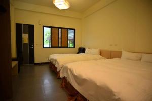 um quarto com 2 camas e uma janela em Shan Jhong You You B&B em Lugu