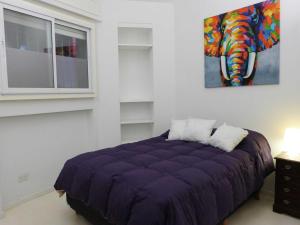 Dormitorio con cama morada y pintura en la pared en La mejor ubicación en Buenos Aires