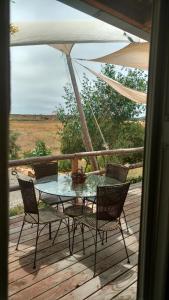 a table and chairs on a deck with an umbrella at Vinofilia Wine Country Inn in Valle de Guadalupe