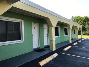 a green building with white doors and a parking lot at Apollo Inn - Cocoa in Cocoa