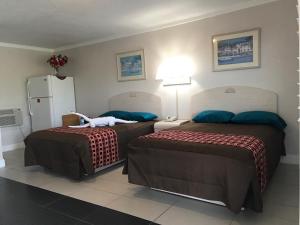 a hotel room with two beds and a refrigerator at Apollo Inn - Cocoa in Cocoa