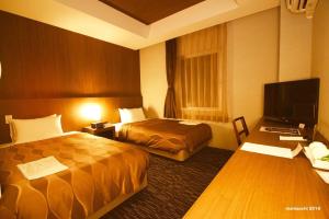 a hotel room with two beds and a television at Hotel Lexton Tanegashima in Nishinoomote