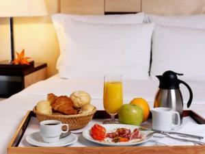 エカテリンブルクにあるホテル ドゥヴァリェツ スヴァデブのベッドの上に朝食用の食材とジュースをトレイ