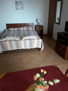 a bedroom with a bed and a table with flowers on it at Yialos Apartments in Pissouri