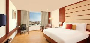 a hotel room with a large bed and a window at Lemon Tree Hotel Shimona Chennai in Chennai