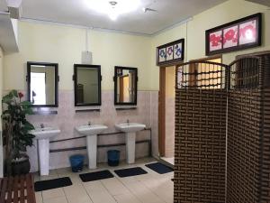 a bathroom with three sinks and mirrors on the wall at TJ Lodge in Cameron Highlands