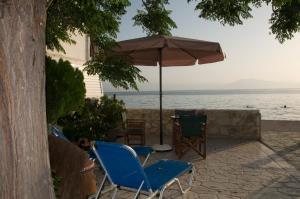 two chairs and an umbrella on a patio by the water at Iria Bay in Iria