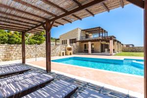 an external view of a house with a swimming pool at Poseidon Villa, nestled in the picturesque south, By ThinkVilla in Lefkogeia