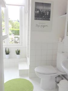 uma casa de banho com um WC branco e um tapete verde em La Maison de famille les Alizés em Le Crotoy