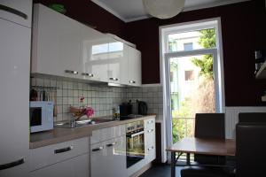 a kitchen with white cabinets and a table and a window at Pension Isabel No2 in Bremen