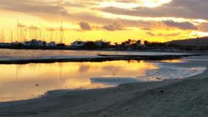 a sunset over a beach with boats in the water at Olosuites in Limassol
