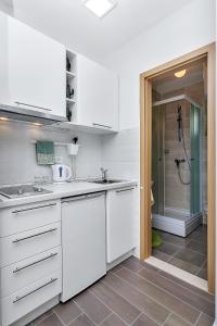 une cuisine avec des placards blancs et une douche à l'italienne dans l'établissement Apartments Franzeta, à Makarska